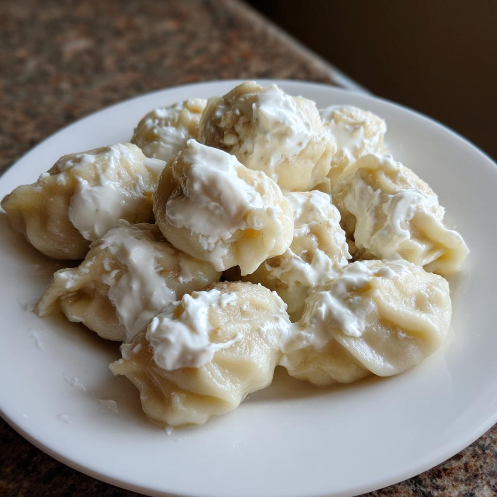 Ein Teller voller Russischer Pelmeni mit Sauerrahm, appetitlich angerichtet.