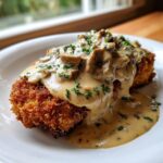 Goldbraunes paniertes Schnitzel übergossen mit cremiger Pilz-Käsesauce und Petersilie.