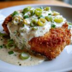Knuspriges Schnitzel übergossen mit cremiger Rahm-Lauch-Sauce und frischen Lauchzwiebelringen.