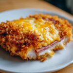 Nahaufnahme von saftigem Schnitzel überbacken mit Käse und Schinken, goldbraun paniert.
