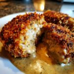 Nahaufnahme von paniertem Schnitzel, das aufgeschnitten ist und die cremige Zwiebel-Senf-Sahnesauce herausfließt.