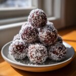 Ein Haufen selbstgemachter Schoko-Kokos-Trüffel ohne Backen, dick in Kokosraspeln gewälzt.