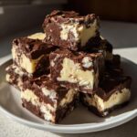 Ein Stapel von selbstgemachtem Cookie-Dough-Fudge mit dunkler Schokolade und heller Vanillefüllung, appetitlich angerichtet.