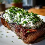 Ein perfekt gebratenes Steak mit einer großzügigen Schicht Zitronen-Knoblauch-Joghurt und frischen Kräutern.