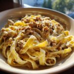 Nahaufnahme von Bandnudeln mit Hackfleisch und cremiger Frischkäsesauce, bestreut mit Pfeffer.