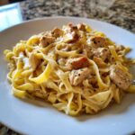 Teller mit cremigen Bandnudeln mit Hähnchenstücken und Kräutern – das perfekte Gericht.