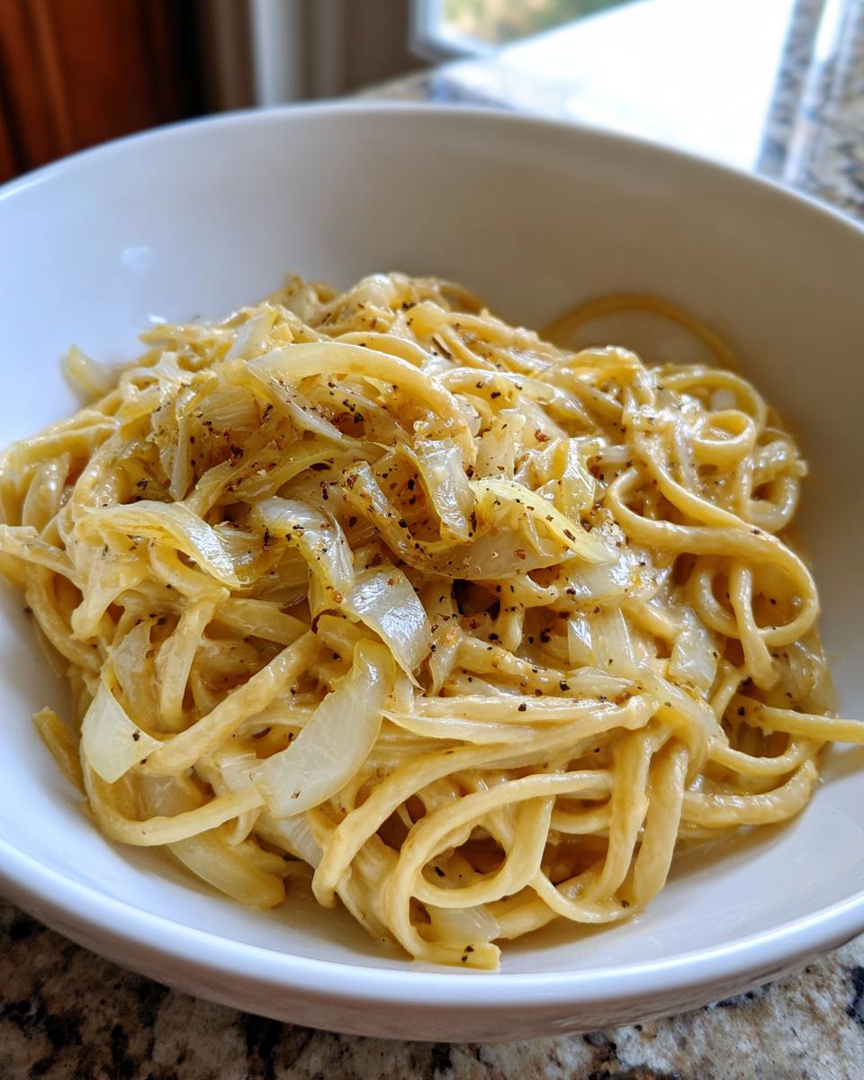 Nahaufnahme einer cremigen Portion Cremige Fenchel-Pasta mit karamellisierten Zwiebeln und viel schwarzem Pfeffer.