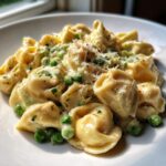 Nahaufnahme von Cremige Tortellini mit Erbsen in einer hellen Sahnesauce, bestreut mit Parmesan.