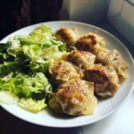 Gebratene Eiernockerl mit grünem Salat, appetitlich angerichtet und mit Pfeffer bestreut.