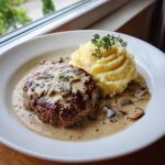 Teller mit saftigen Frikadellen in Champignonrahm und einem Klecks cremigem Püree.