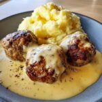 Drei saftige Frikadellen in cremiger Senfrahmsoße mit einem Klecks Kartoffelpüree.