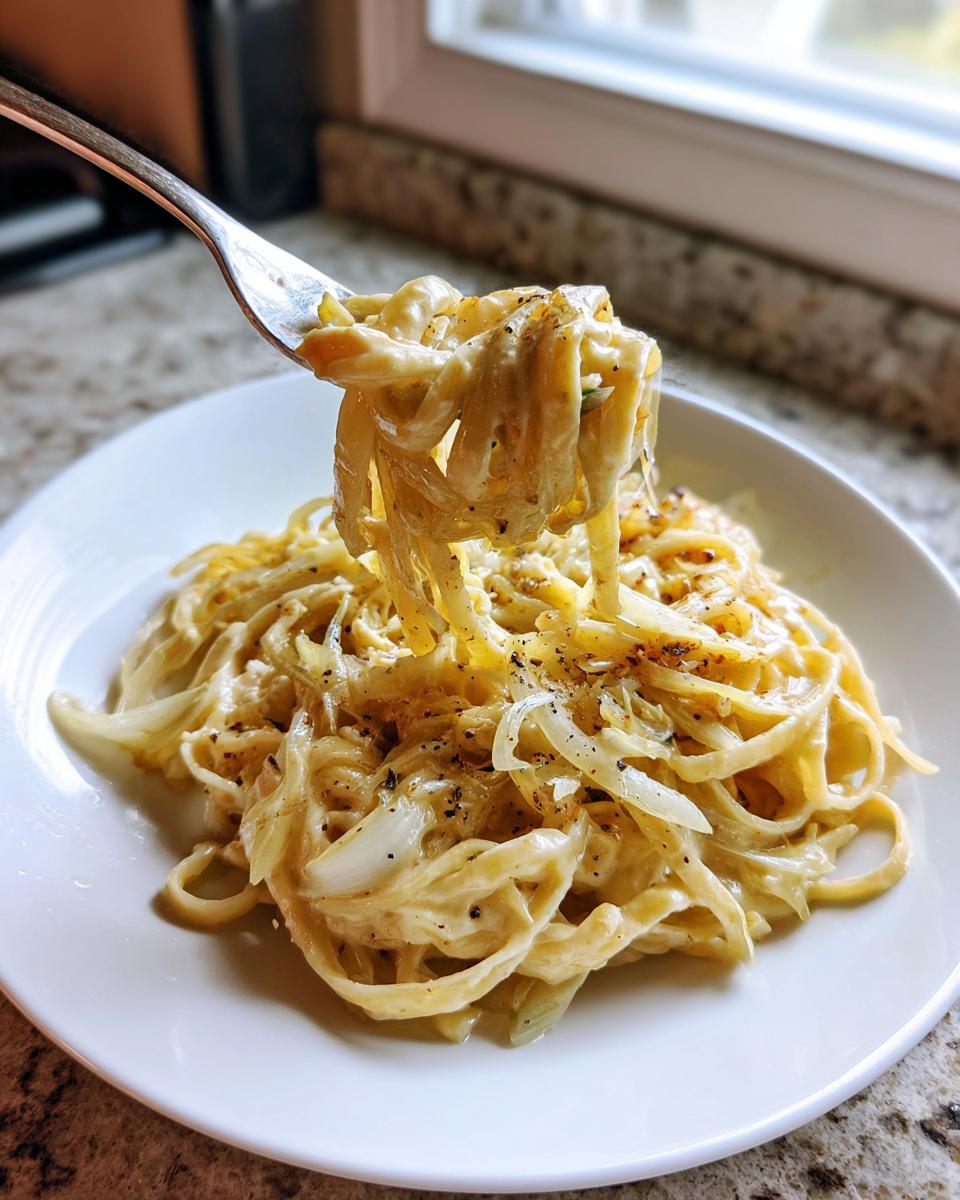 Eine Gabel voller cremiger Fenchel-Pasta wird hochgehoben, reichlich mit frisch gemahlenem Pfeffer bestreut.