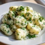 Nahaufnahme von fluffigen Gnocchi mit Frischkäse und vielen frischen Kräutern.