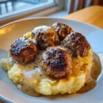 Fünf saftige Hackbällchen mit cremiger Rahmsauce auf einem Bett aus fluffigem Kartoffelpüree.