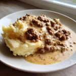 Ein Teller mit cremiger Hackfleischpfanne in Sahnesauce und lockerem Kartoffelstampf.