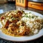 Teller mit saftigem Hähnchen in Senfrahm und einer Portion fluffigem Butterreis, garniert mit Petersilie.