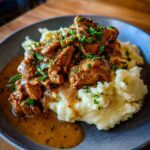 Teller mit cremigem Kartoffelpüree, belegt mit saftigem Gyros und reichlich Metaxasauce, garniert mit Petersilie.