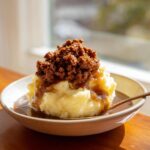 Ein Teller Kartoffelpüree mit cremigem Hackfleisch und viel dunkler Bratensauce.