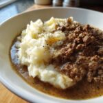 Cremiges Kartoffelpüree mit Rinderhack in Pfefferrahm in einer weißen Schüssel, appetitlich angerichtet.