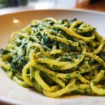 Nahaufnahme von cremigen Nudeln mit Rucola-Frischkäse, üppig bedeckt mit der grünen Soße.