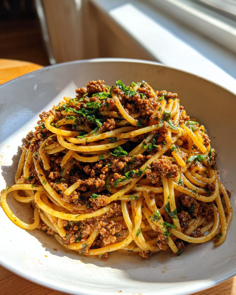 Eine Schüssel Pasta mit Hackfleisch und Kräuterbutter, appetitlich angerichtet und im Sonnenlicht.