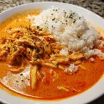 Teller mit cremigem Putengeschnetzeltes mit Paprikarahm und lockerem Reis, bestreut mit Petersilie.