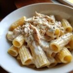 Cremige Rigatoni mit Hähnchenstücken in einer reichhaltigen Schmand-Sauce, garniert mit Kräutern.