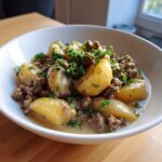 Nahaufnahme einer Schüssel mit Rinderhack-Kartoffelpfanne in Rahm, garniert mit frischer Petersilie.