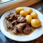 Teller mit saftigen Rinderstreifen in cremiger Knoblauchrahmsoße und Salzkartoffeln.