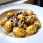 Nahaufnahme von Schupfnudeln mit Rinderstreifen in Sahne, übergossen mit einer cremigen Senfsauce und Petersilie.