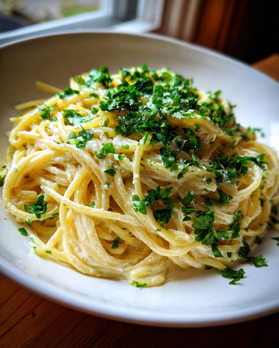 Nahaufnahme von cremigen Spaghetti mit Zitronen-Sahne, reichlich garniert mit frischer Petersilie.
