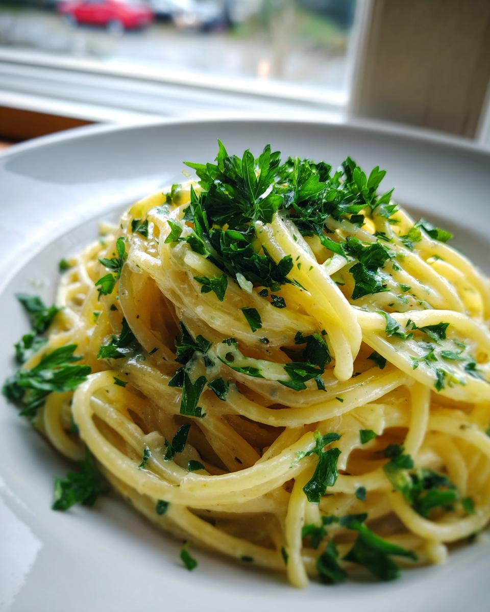 Nahaufnahme von cremigen Spaghetti mit Zitronen-Sahne, reichlich mit frischer Petersilie garniert.
