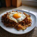 Ein Teller Tiroler Gröstl mit Spiegelei, goldbraun gebratene Kartoffeln und Fleisch mit flüssigem Eigelb.