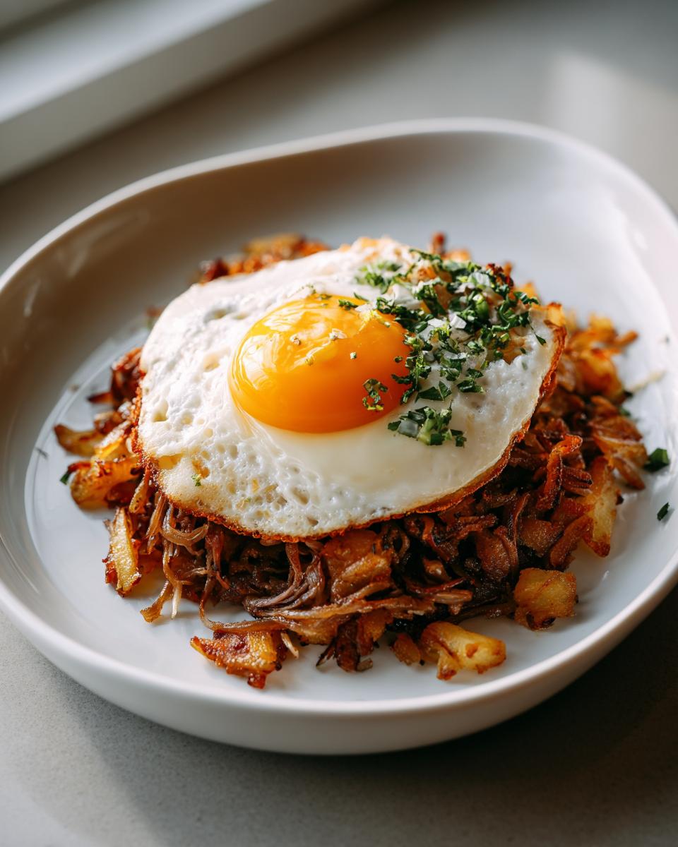 Ein appetitliches Tiroler Gröstl mit Spiegelei, garniert mit frischer Petersilie, serviert auf einem weißen Teller.