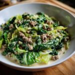 Cremige Wirsing-Hackfleisch-Pfanne in Sahne, serviert in einer weißen Schüssel auf Holzuntergrund.